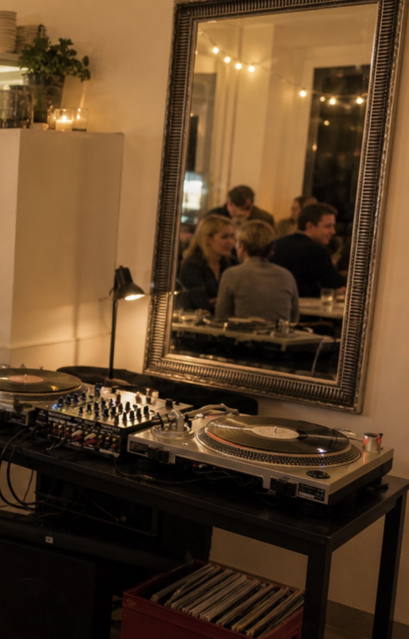 A DJ-pult a kávézóban, a tükörben a beszélgető vendégek és a fényfüzér